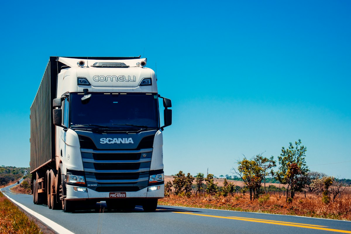 Caminhão prancha transportando equipamento industrial pesado em rodovia brasileira
